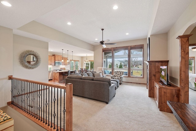 living area with baseboards, recessed lighting, arched walkways, light carpet, and ceiling fan with notable chandelier