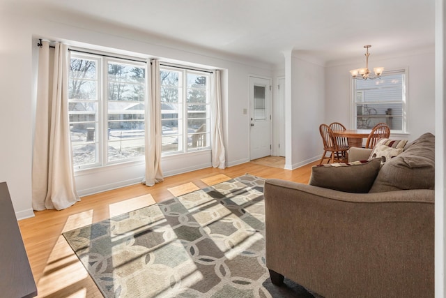 living room with a wealth of natural light, a chandelier, and wood finished floors