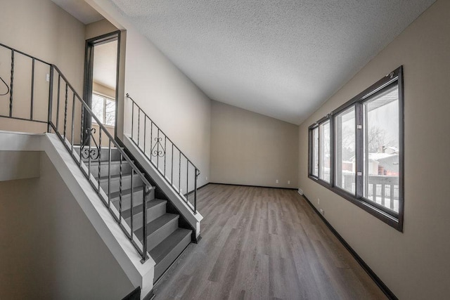 stairway featuring a textured ceiling, lofted ceiling, and hardwood / wood-style floors