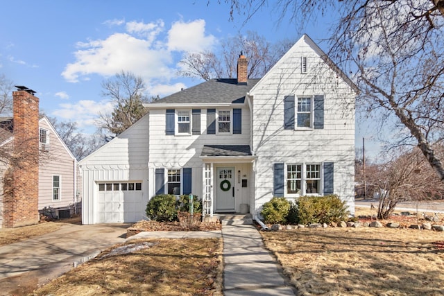 traditional-style home featuring a garage, concrete driveway, a shingled roof, and a chimney