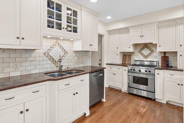 kitchen with appliances with stainless steel finishes, a sink, glass insert cabinets, and white cabinets