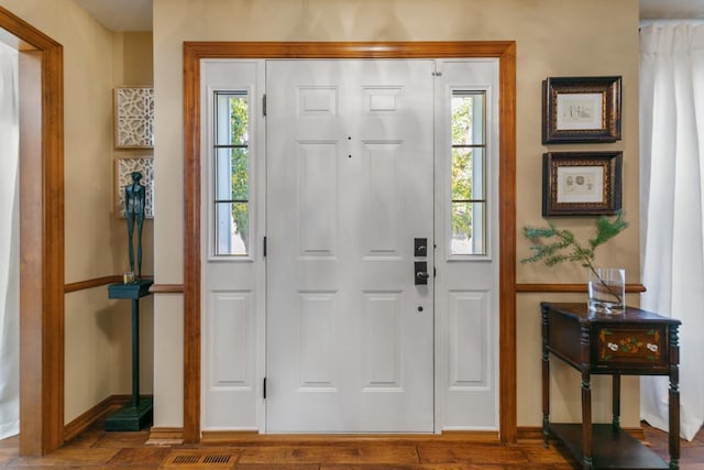 foyer entrance with visible vents, baseboards, and wood finished floors