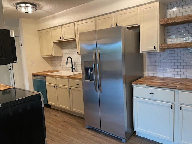 kitchen featuring wood counters, white cabinetry, stainless steel appliances, and sink