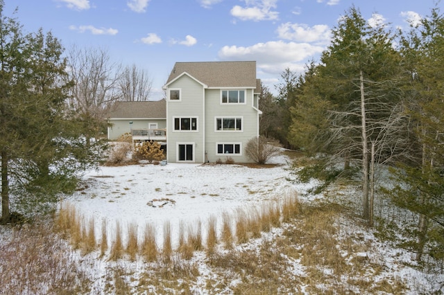 snow covered back of property featuring a deck