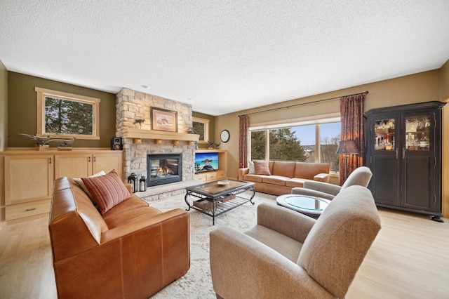 living room featuring a fireplace, light hardwood / wood-style floors, a textured ceiling, and a healthy amount of sunlight