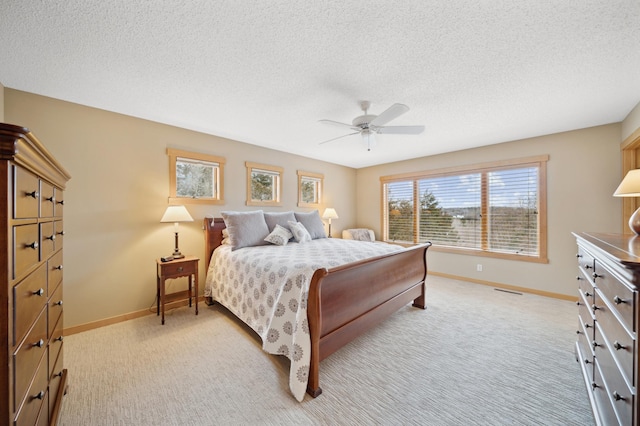 bedroom featuring a textured ceiling, light carpet, and ceiling fan