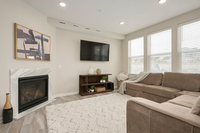 living area featuring light wood-type flooring, a high end fireplace, visible vents, and recessed lighting