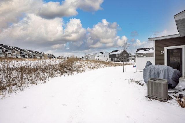 yard covered in snow featuring cooling unit, a residential view, and fence