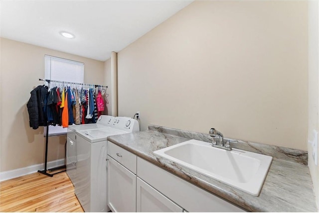 laundry room featuring cabinets, washing machine and dryer, sink, and light hardwood / wood-style floors