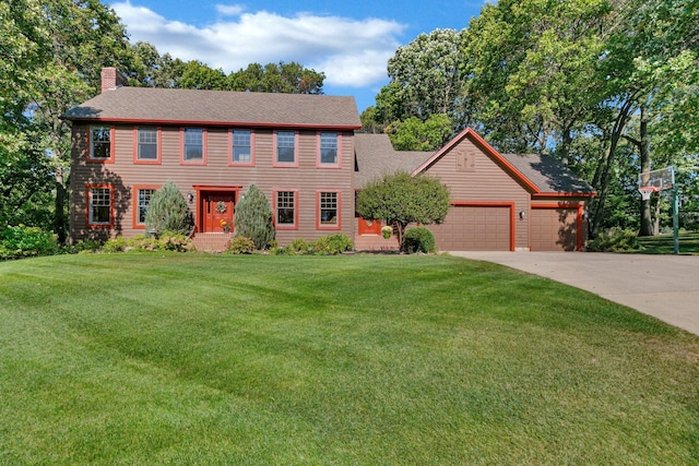 colonial house featuring a garage, a chimney, concrete driveway, and a front yard