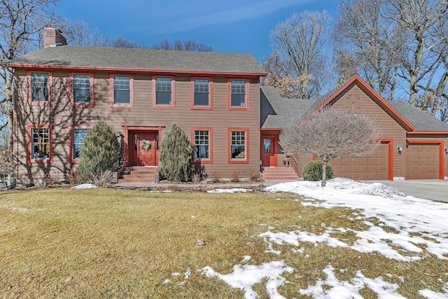 colonial house featuring aphalt driveway, a lawn, a chimney, and an attached garage