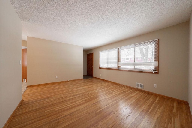 unfurnished room featuring light wood-type flooring and a textured ceiling