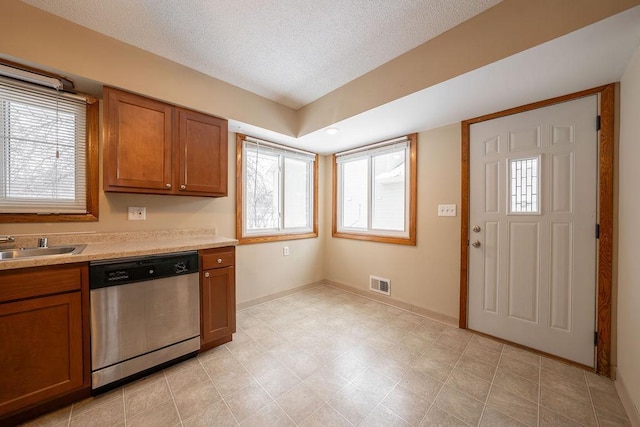 kitchen with a textured ceiling, sink, a healthy amount of sunlight, and dishwasher