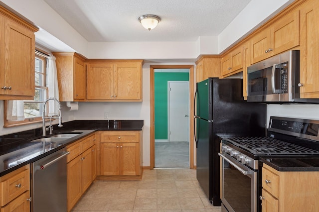 kitchen featuring stainless steel appliances, a textured ceiling, and sink