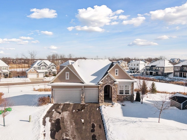 view of front of home with a garage, stone siding, driveway, and a residential view