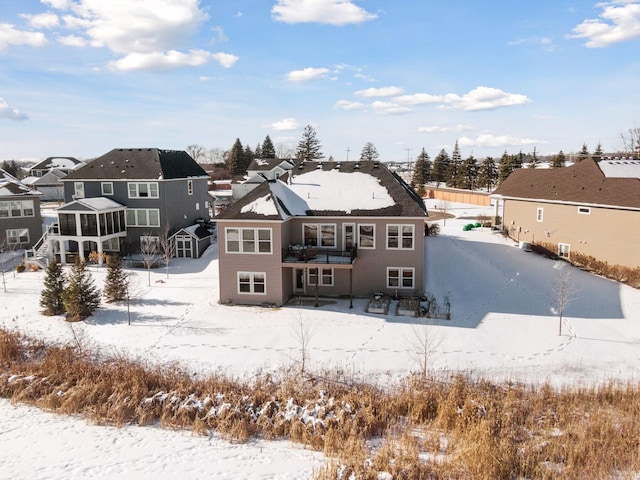 snow covered rear of property with a residential view