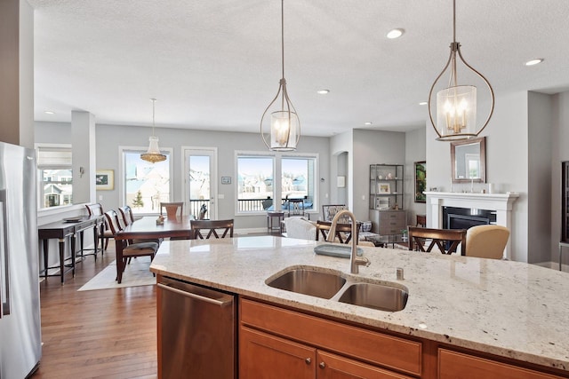 kitchen with light stone countertops, stainless steel appliances, a sink, and decorative light fixtures