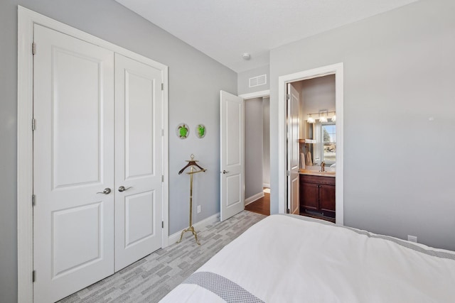 bedroom with a closet, connected bathroom, visible vents, and baseboards