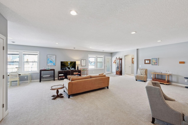 living area with arched walkways, recessed lighting, baseboards, and light colored carpet