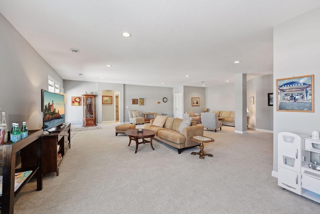 living area with arched walkways, light carpet, baseboards, and recessed lighting