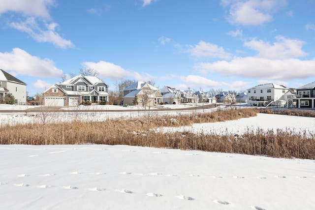 yard layered in snow featuring a garage and a residential view