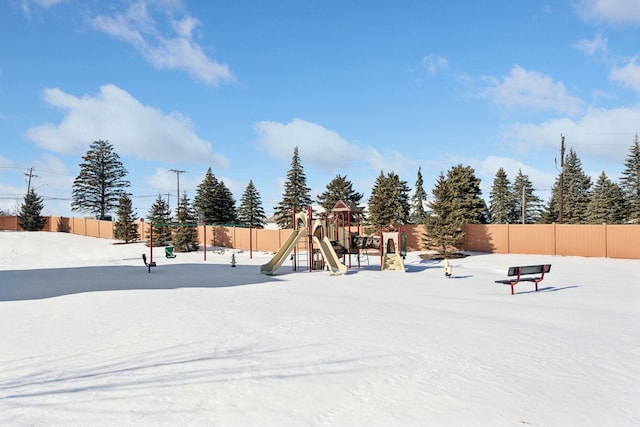 snow covered playground with playground community and fence