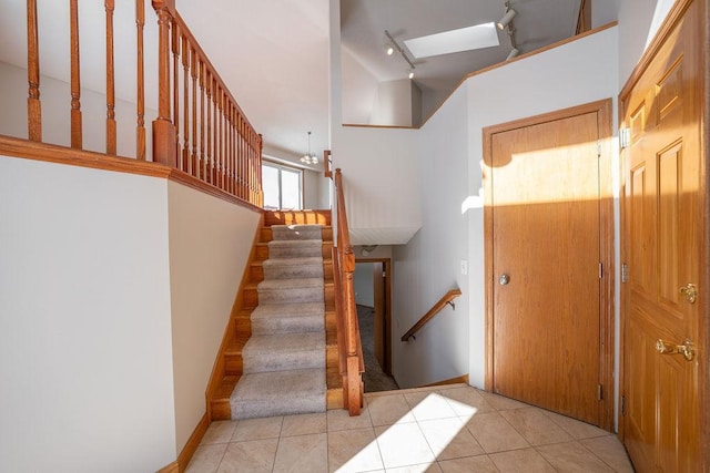 staircase with track lighting and tile patterned flooring