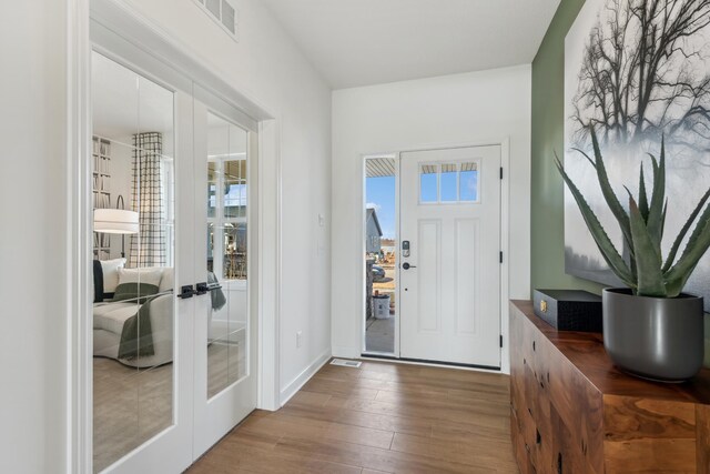 foyer entrance with french doors, visible vents, baseboards, and wood finished floors