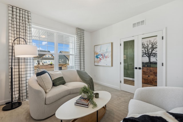 living room featuring light colored carpet, french doors, visible vents, and baseboards