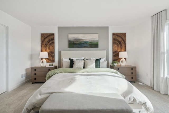 bedroom featuring baseboards, visible vents, and light colored carpet