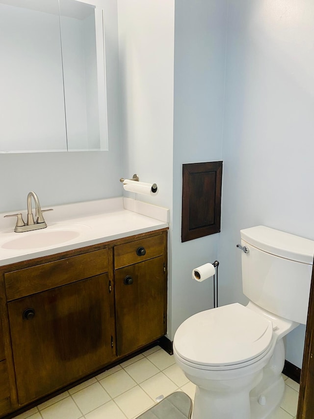 bathroom with toilet, vanity, and tile patterned flooring