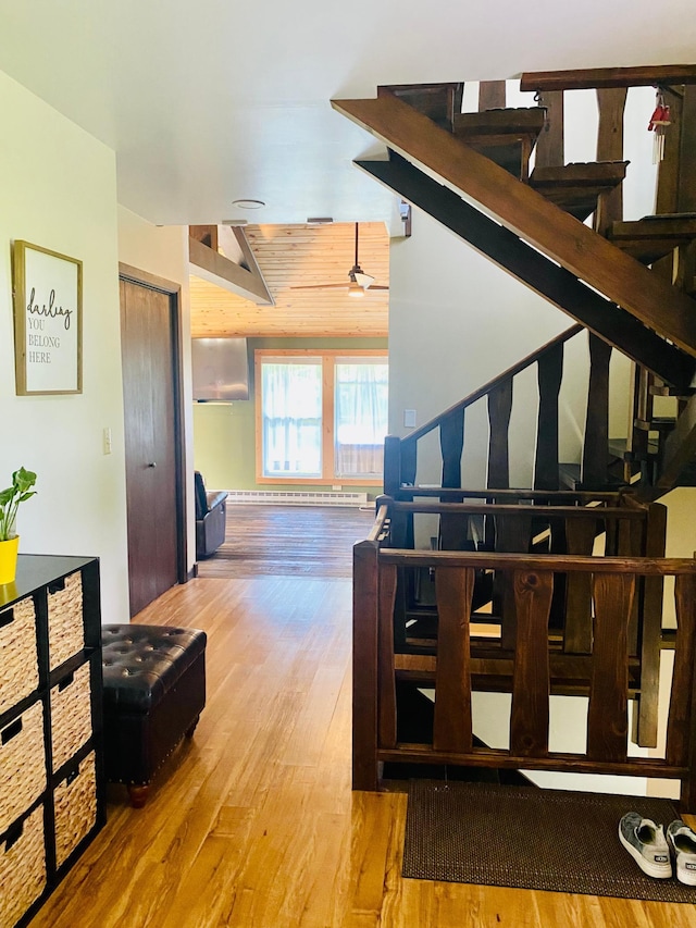 staircase with hardwood / wood-style flooring, lofted ceiling, and baseboard heating