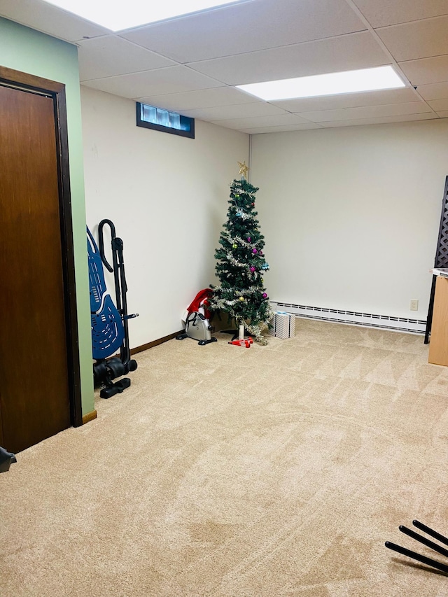 basement featuring a baseboard heating unit, a drop ceiling, and carpet floors