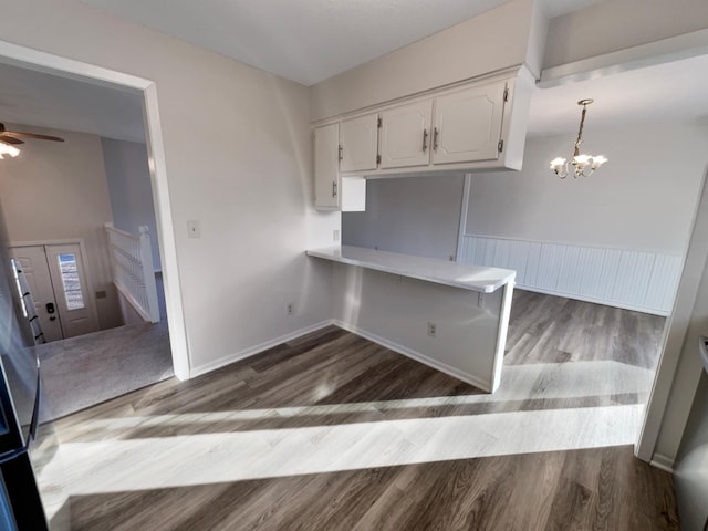 kitchen featuring hardwood / wood-style floors, white cabinetry, ceiling fan with notable chandelier, kitchen peninsula, and hanging light fixtures