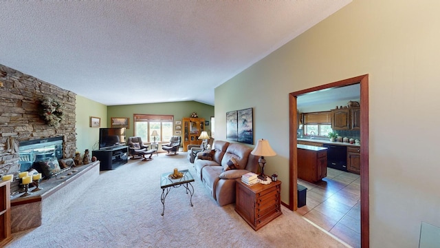 living area with a fireplace, light tile patterned floors, light colored carpet, vaulted ceiling, and a textured ceiling