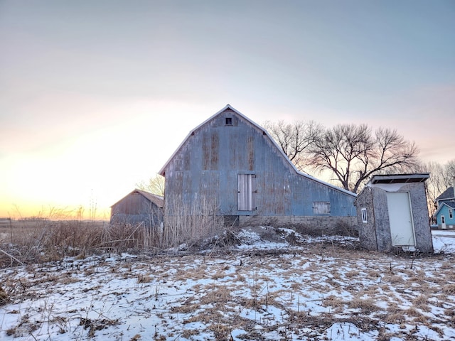 snow covered structure with an outbuilding and a barn