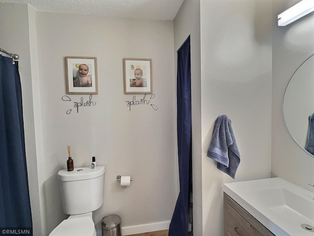 full bath with baseboards, a textured ceiling, vanity, and toilet