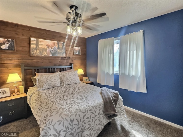 carpeted bedroom featuring wooden walls, a textured ceiling, baseboards, and a ceiling fan