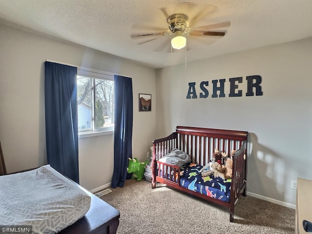 carpeted bedroom featuring visible vents, a textured ceiling, baseboards, and a ceiling fan