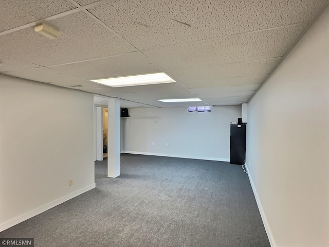 finished basement with a drop ceiling, baseboards, and carpet