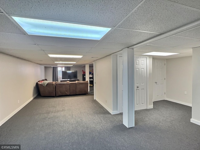 finished below grade area with a paneled ceiling, baseboards, and carpet