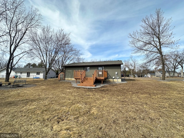 rear view of house featuring a yard, a wooden deck, and fence