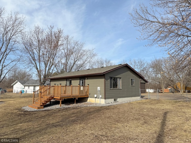 rear view of house featuring a yard, fence, and a wooden deck