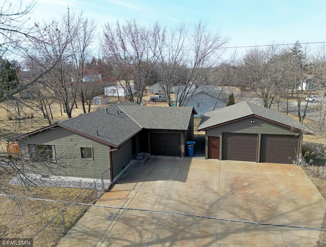 view of front facade featuring a detached garage and roof with shingles