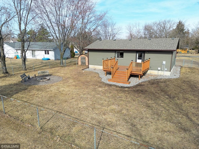 back of house featuring a deck, a fenced backyard, a lawn, and roof with shingles