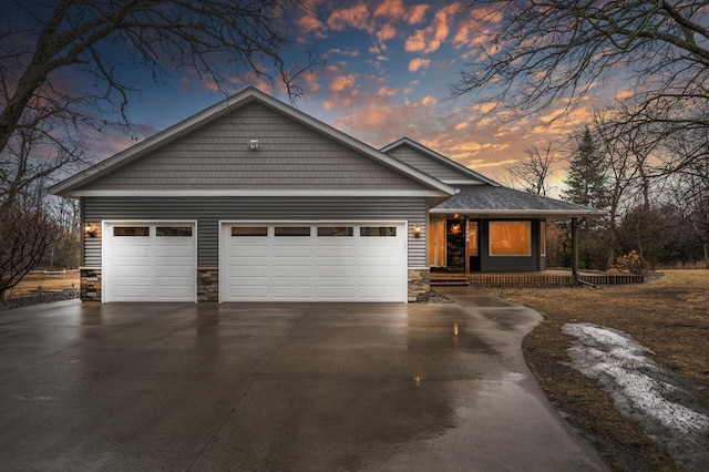 view of front of house featuring a garage, concrete driveway, and stone siding