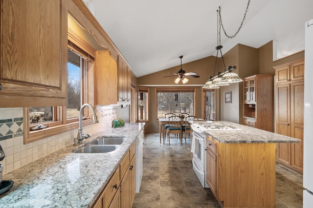 kitchen featuring white appliances, plenty of natural light, a kitchen island, and a sink