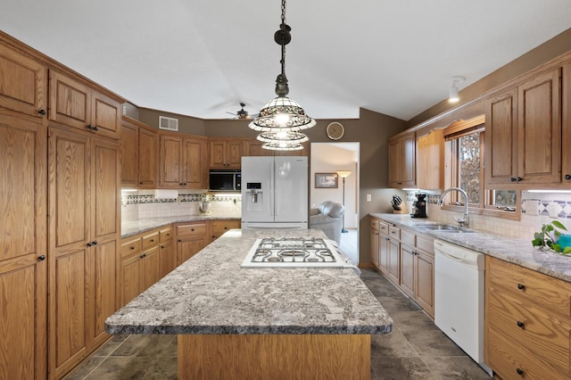 kitchen featuring white appliances, a kitchen island, a sink, visible vents, and tasteful backsplash