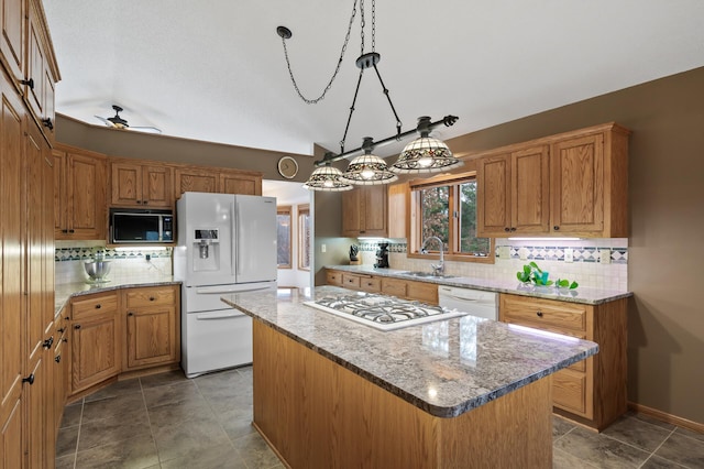 kitchen with lofted ceiling, white appliances, a sink, backsplash, and a center island