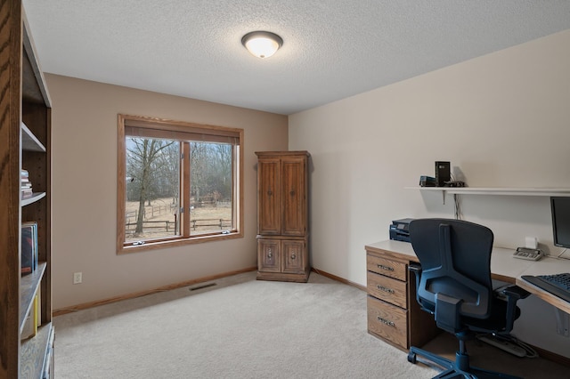 office area with light colored carpet, visible vents, a textured ceiling, and baseboards